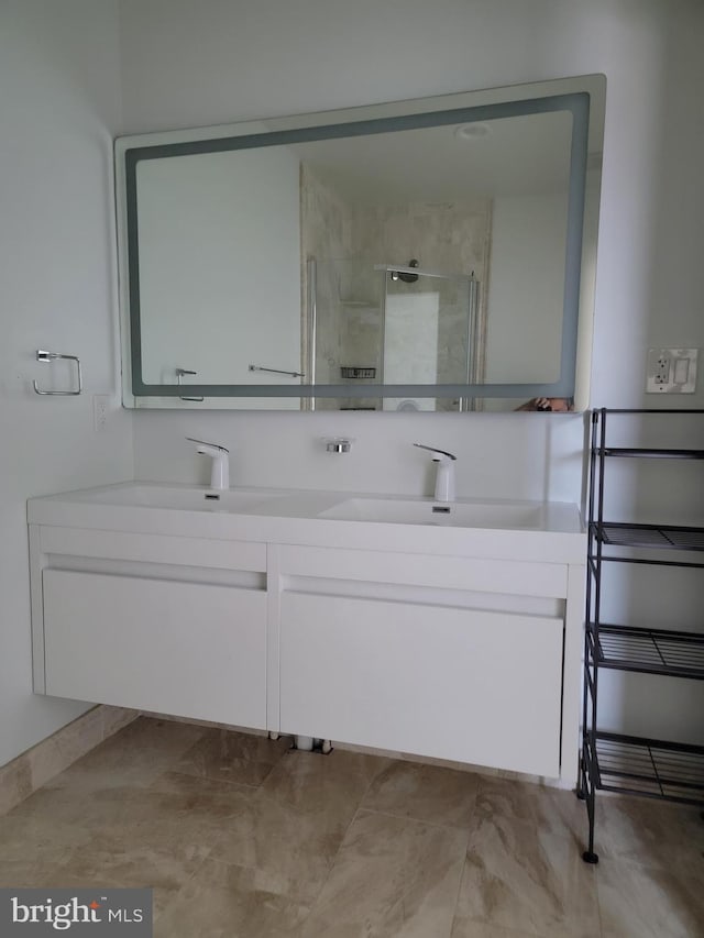 full bath featuring tiled shower, a sink, and double vanity