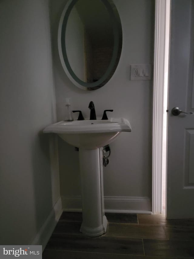 bathroom with wood tiled floor, a sink, and baseboards