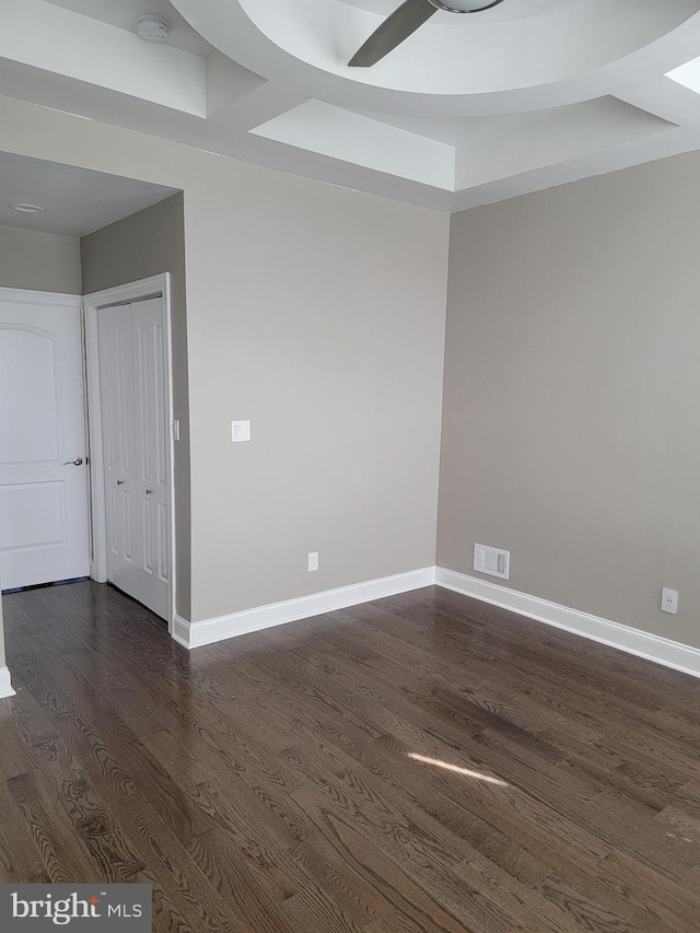 spare room featuring dark wood-style floors, baseboards, visible vents, and ceiling fan