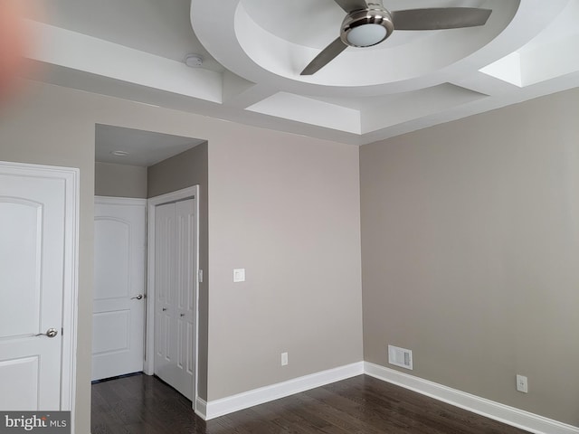 unfurnished bedroom with ceiling fan, dark wood finished floors, visible vents, and baseboards