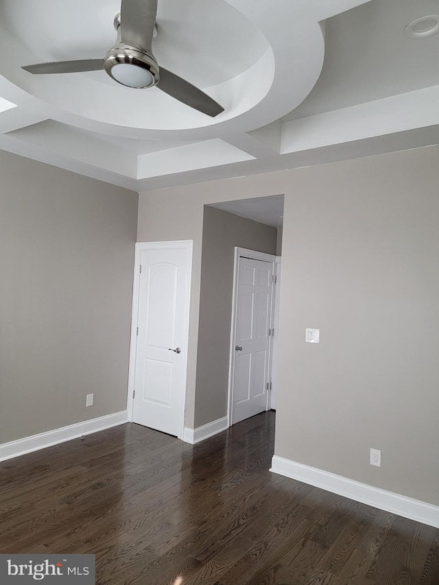 spare room featuring dark wood-style floors, ceiling fan, and baseboards