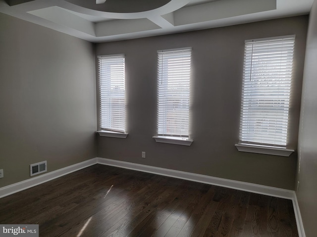 spare room featuring dark wood-style flooring, visible vents, and baseboards