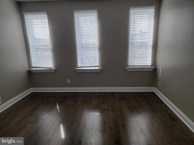 spare room featuring dark wood finished floors and baseboards