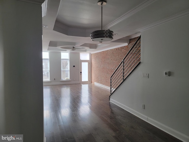 entryway featuring baseboards, brick wall, stairway, dark wood-type flooring, and crown molding