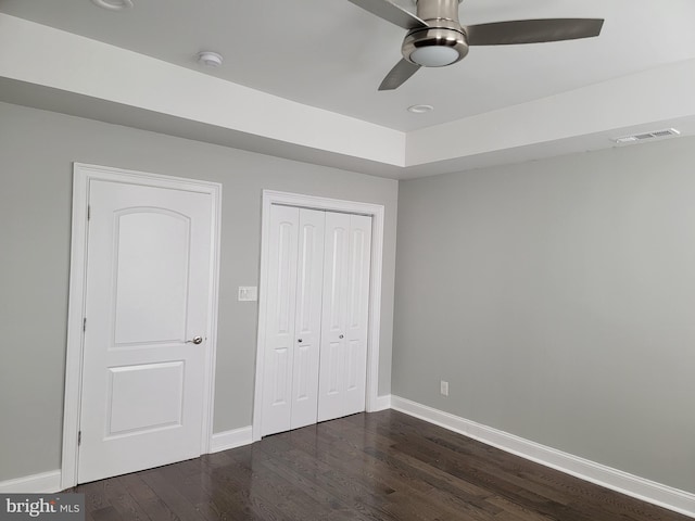 unfurnished bedroom with dark wood-style flooring, a closet, visible vents, and baseboards