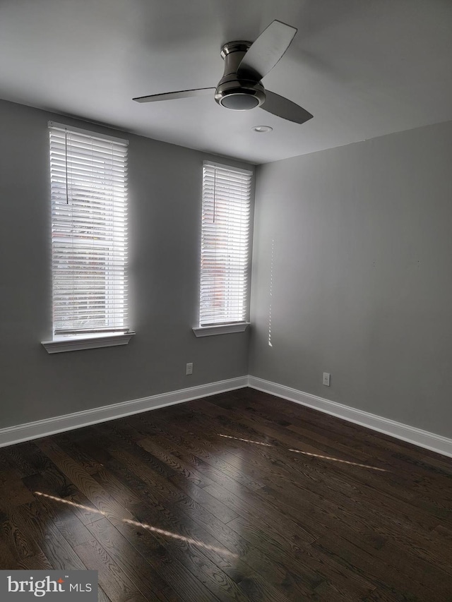 spare room featuring dark wood-type flooring, ceiling fan, and baseboards