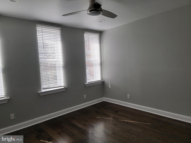 empty room with dark wood-style floors, a ceiling fan, and baseboards