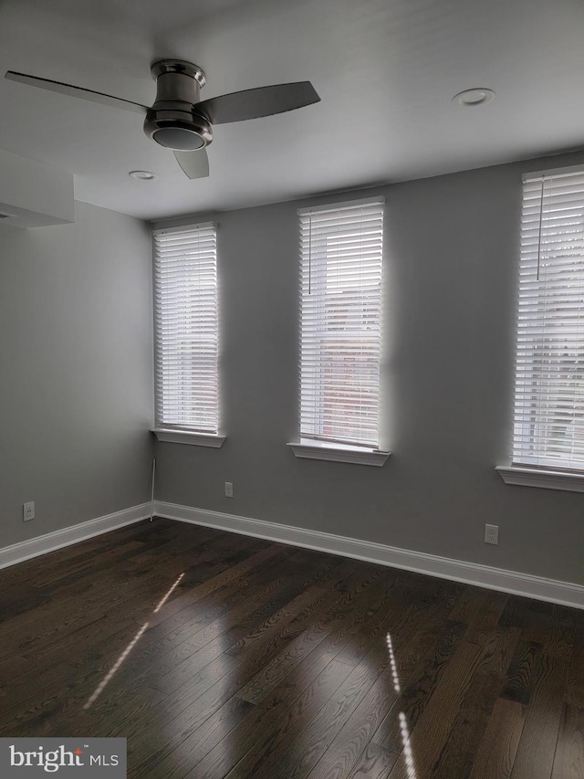 spare room with ceiling fan, dark wood finished floors, and baseboards