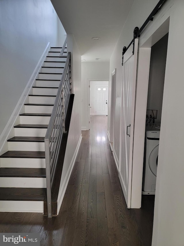 hall with stairway, a barn door, washer / clothes dryer, and dark wood-type flooring