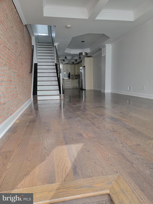 interior space featuring a tray ceiling, hardwood / wood-style floors, ornamental molding, baseboards, and stairs