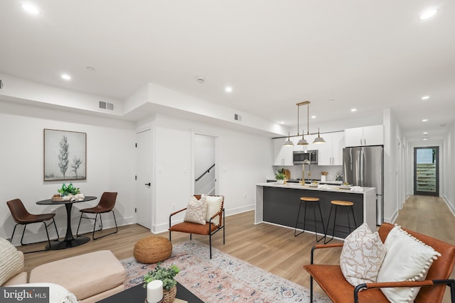 living area with light wood-type flooring, visible vents, and recessed lighting
