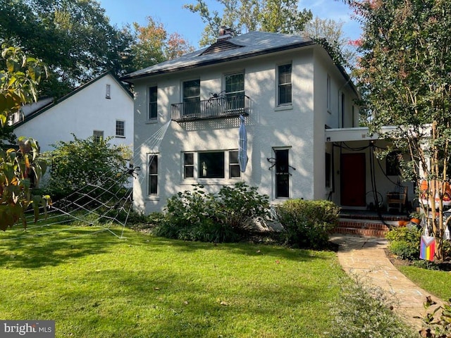 view of front of property featuring a front lawn, a chimney, and stucco siding