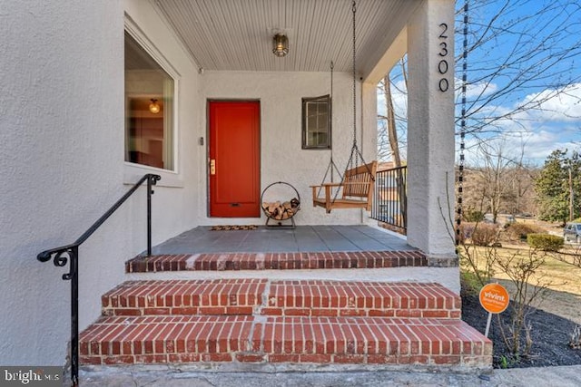 doorway to property featuring stucco siding and covered porch