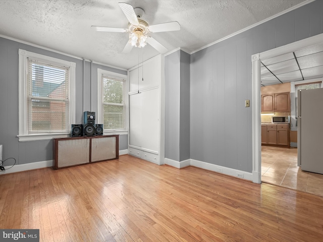 unfurnished office featuring crown molding, ceiling fan, a textured ceiling, and light wood finished floors