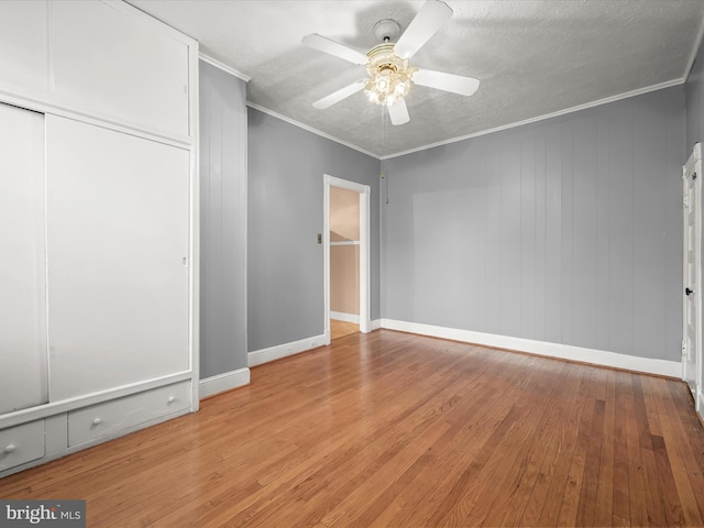 unfurnished bedroom with a closet, light wood-style flooring, ornamental molding, ceiling fan, and baseboards