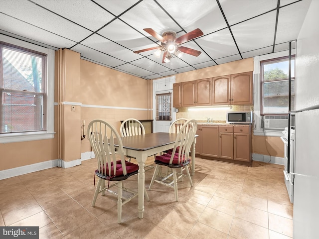 dining room with a wealth of natural light, a paneled ceiling, ceiling fan, and baseboards