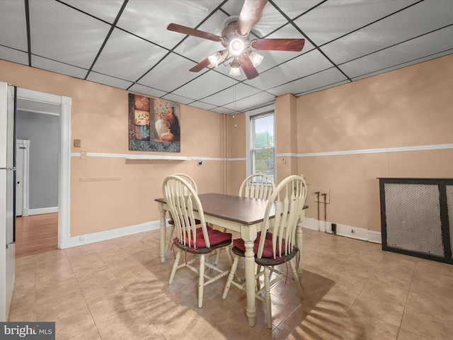 tiled dining room featuring a paneled ceiling, a ceiling fan, and wainscoting