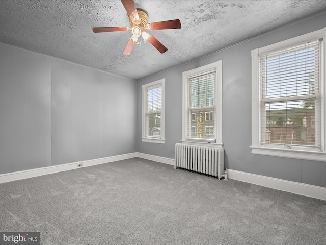 carpeted spare room with a textured ceiling, baseboards, a ceiling fan, and radiator