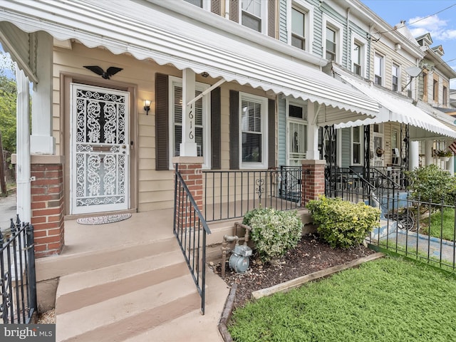 entrance to property with fence and a porch