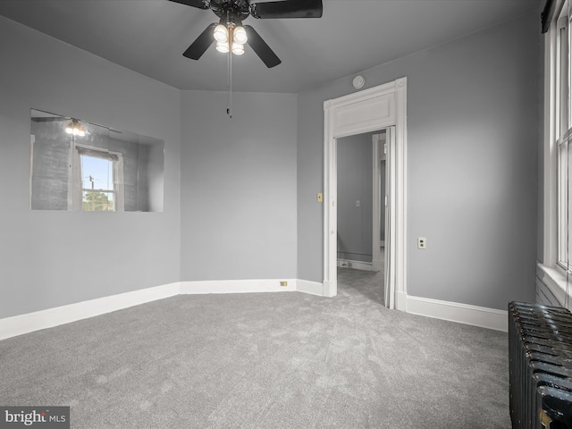 carpeted empty room featuring ceiling fan, radiator, and baseboards