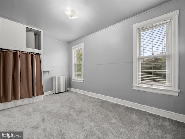 unfurnished room featuring ornamental molding, carpet, a wealth of natural light, and radiator