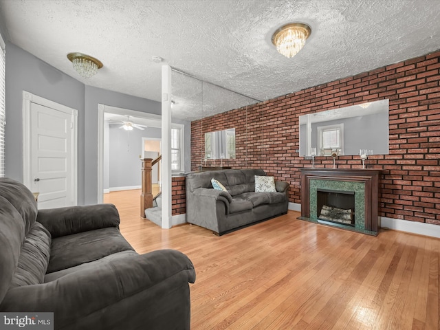 living area with a high end fireplace, brick wall, and hardwood / wood-style flooring