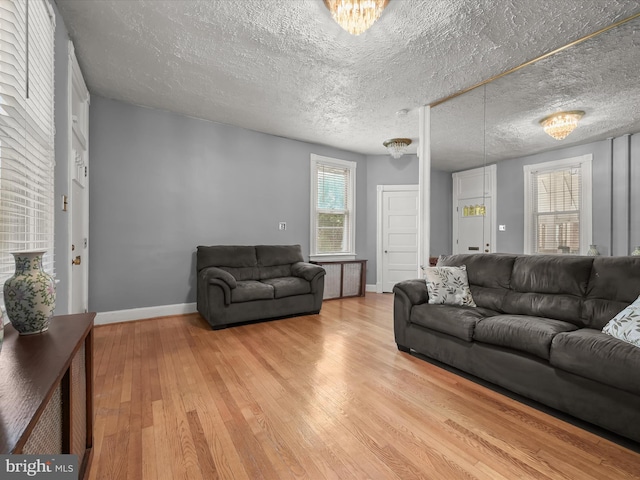 living area featuring light wood-style floors, a textured ceiling, and baseboards