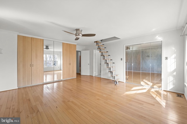 interior space featuring ornamental molding, visible vents, light wood-style flooring, and a ceiling fan