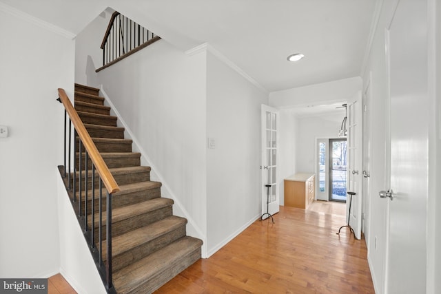 staircase featuring crown molding, baseboards, and wood finished floors