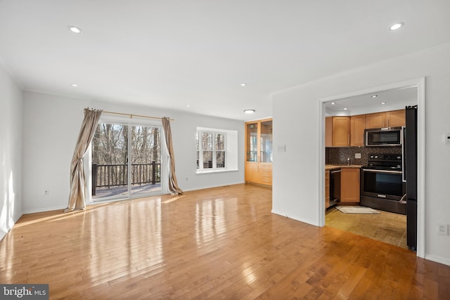 unfurnished living room featuring baseboards, recessed lighting, and light wood-style floors