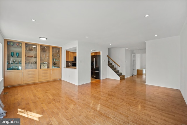 unfurnished living room featuring light wood-type flooring, visible vents, recessed lighting, and stairs