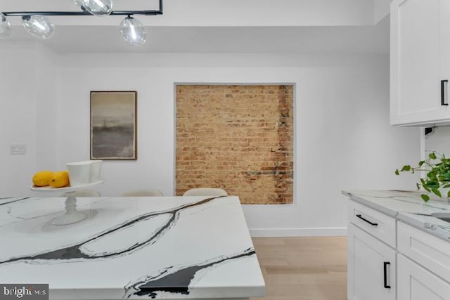 bedroom featuring light wood-type flooring, brick wall, and baseboards