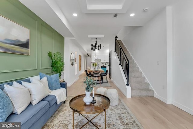 living room with stairway, light wood-type flooring, an inviting chandelier, and recessed lighting