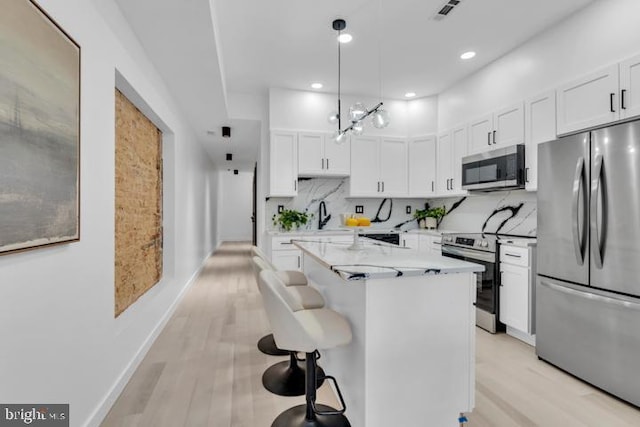 kitchen featuring a center island, visible vents, backsplash, appliances with stainless steel finishes, and white cabinetry