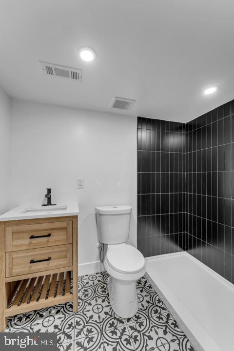 full bath featuring tile patterned flooring, visible vents, toilet, and tiled shower