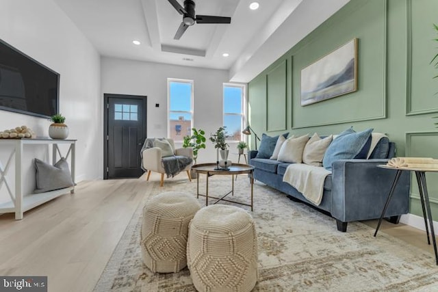 living room with a tray ceiling, wood finished floors, a ceiling fan, and recessed lighting