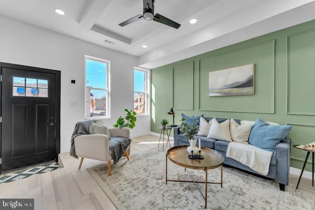 living area featuring light wood finished floors, visible vents, ceiling fan, a decorative wall, and recessed lighting