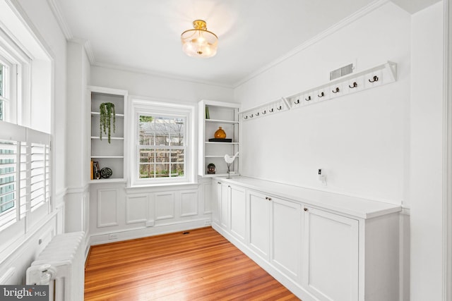 mudroom with crown molding, light wood-style floors, visible vents, and radiator