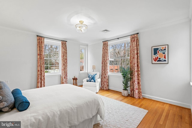 bedroom featuring light wood-style flooring, multiple windows, visible vents, and baseboards