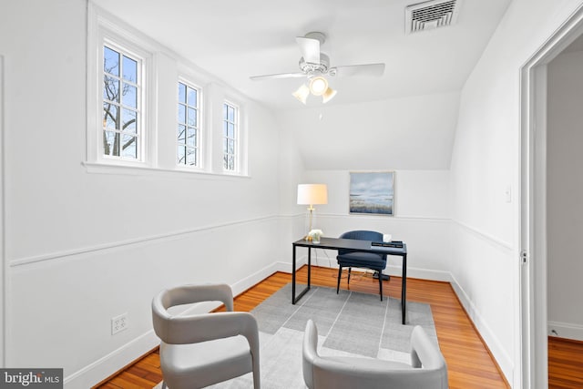 home office featuring baseboards, visible vents, a ceiling fan, wood finished floors, and vaulted ceiling