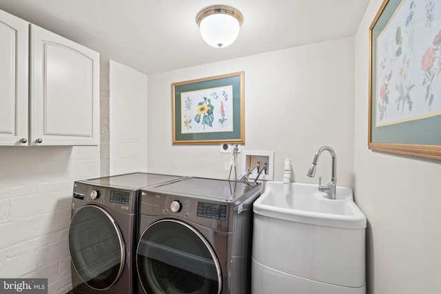 clothes washing area with separate washer and dryer, a sink, cabinet space, and concrete block wall