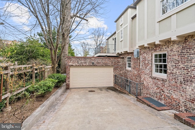 view of property exterior with an attached garage, brick siding, fence, driveway, and stucco siding