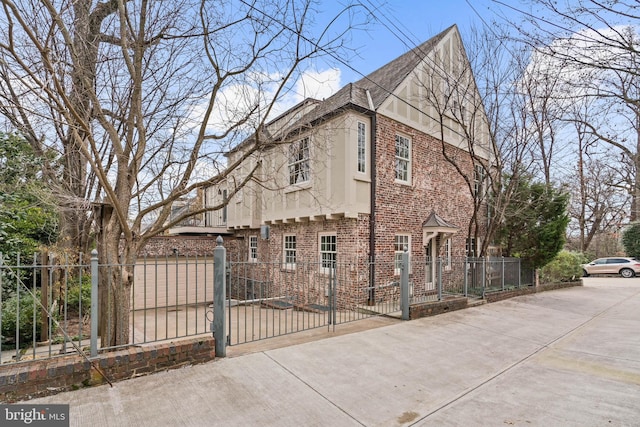 view of side of property with a fenced front yard, a gate, brick siding, and stucco siding