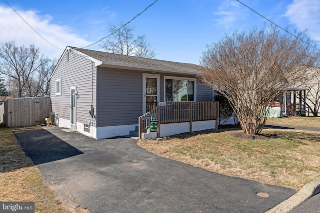 view of front of house featuring a porch, a shingled roof, driveway, and a front yard