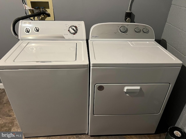 washroom featuring laundry area, concrete block wall, and washer and dryer