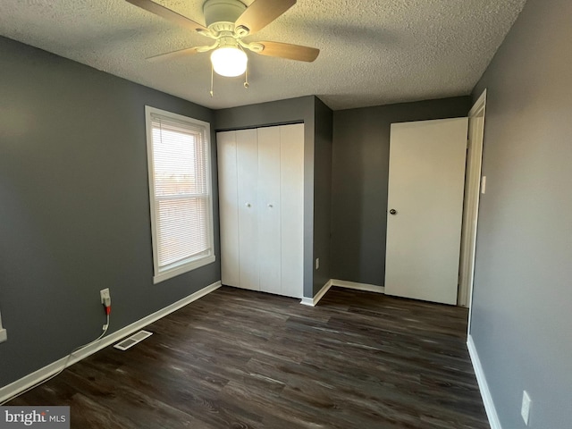 unfurnished bedroom featuring visible vents, baseboards, wood finished floors, a textured ceiling, and a closet