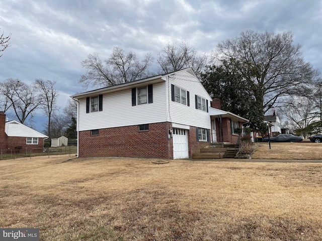 view of side of home with driveway, an attached garage, fence, a yard, and brick siding