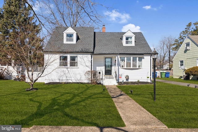 cape cod home featuring a shingled roof, a front yard, and a chimney