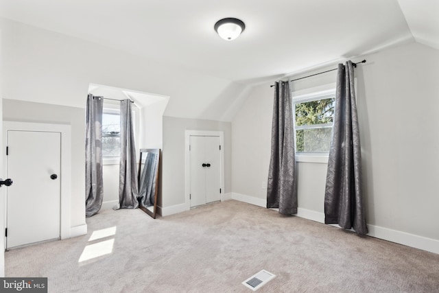 additional living space with lofted ceiling, baseboards, visible vents, and light colored carpet