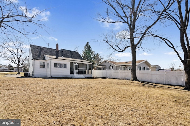 rear view of house featuring roof with shingles, a chimney, central air condition unit, a sunroom, and fence